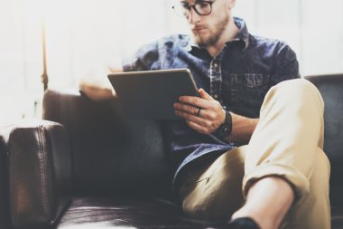 Sakallı pazarlama uzmanı çalışma dijital tablet modern İç Tasarım Loft Office.Man klasik kanepe kullanımı çağdaş cihaz Hand.Blurred Background.Creative Process Business Startup Idea dinlenmek.