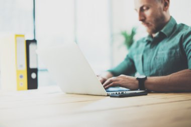 Sakallı hipster ahşap masa dizüstü Modern İç Tasarım Loft Office.Man İş Coworking Studio, çağdaş Notebook, klavye yazarak kullanın çalışma. Bulanık Arka Plan.Yaratıcı İş Başlangıç Fikri.