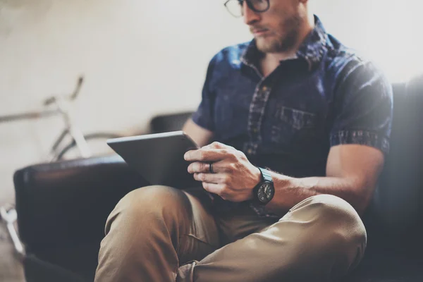 Bearded Guy arbets tablett enhet modern inredning Loft byggnad. man kylning Vintage soffa använda samtida dator hand. suddig bakgrund. Creative Business Startup idé. horisontell, Filmeffek — Stockfoto