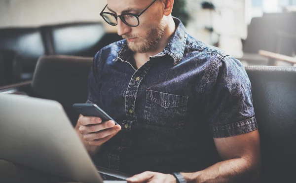 Gerente de risco bem sucedido trabalhando Laptop design de interiores moderno Loft Office.Men trabalho Sofá Vintage, Usando contemporânea Smartphone Hand Texting.Blurred Background.Business Startup Idea Process.Film efeito . — Fotografia de Stock