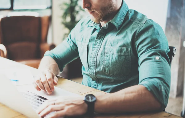 Barbudo hipster trabalhando mesa de madeira laptop Design moderno Interior Office.Man Trabalho Coworking Studio, Use Notebook contemporâneo, tecla de digitação keyboard.Blurred Background.Creative processo Business Startup Idea . — Fotografia de Stock