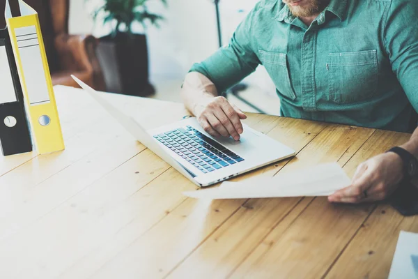 Barbudo comerciante mesa de trabajo de madera portátil moderno diseño de interiores Loft Office.Man Trabajo Coworking Studio, Utilice el cuaderno contemporáneo, tecleando el teclado Informe fondo borroso. — Foto de Stock