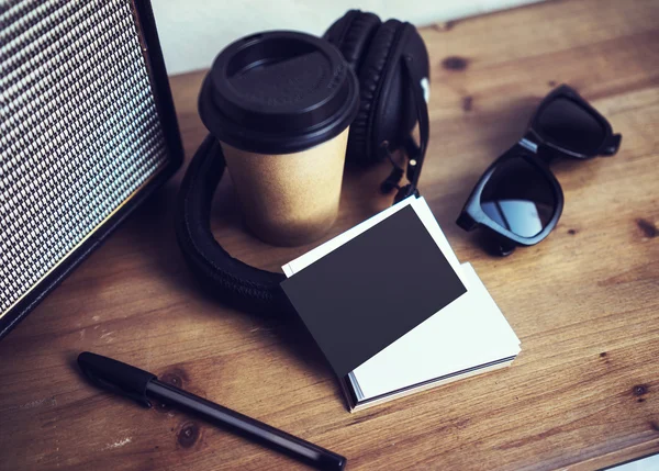 Close-up stack leeg papier visitekaartje mockup hout tabel. Kraft take away koffie kopje Coworking Studio. moderne koptelefoon draagbare speaker zonnebril interieur Cafe achtergrond. Lifestyle mock up voorwerpen. — Stockfoto