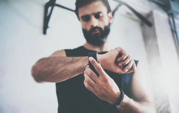 Close-up Shot Young Bearded Sportive Man Después de la sesión de entrenamiento Comprueba los resultados de fitness Smart Watch.Adult Guy usa un brazalete de rastreo deportivo.Gimnasio de entrenamiento duro. . — Foto de Stock