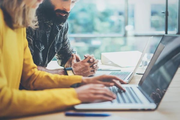 Deux collègues modernes discutent ensemble pendant le processus de travail.Young Business People Meeting Concept.Discussion Bureau de projet de démarrage. Homme barbu regardant ordinateur portable, femme dactylographiant table de bureau en bois. . — Photo