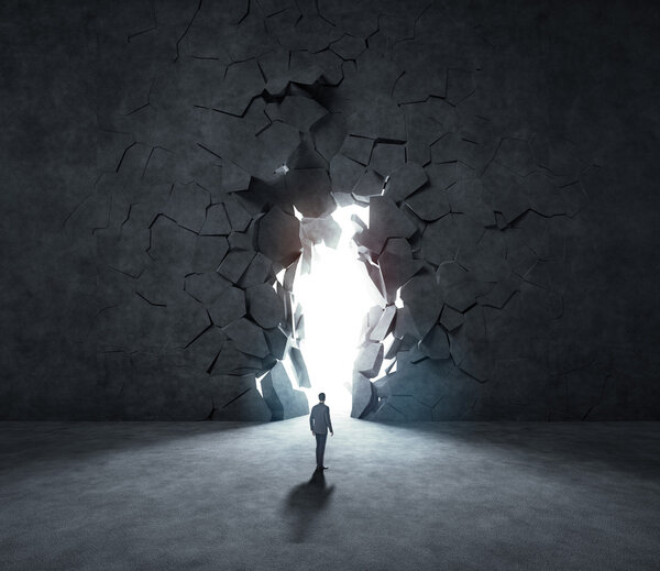 Businessman breaking trough a stone wall