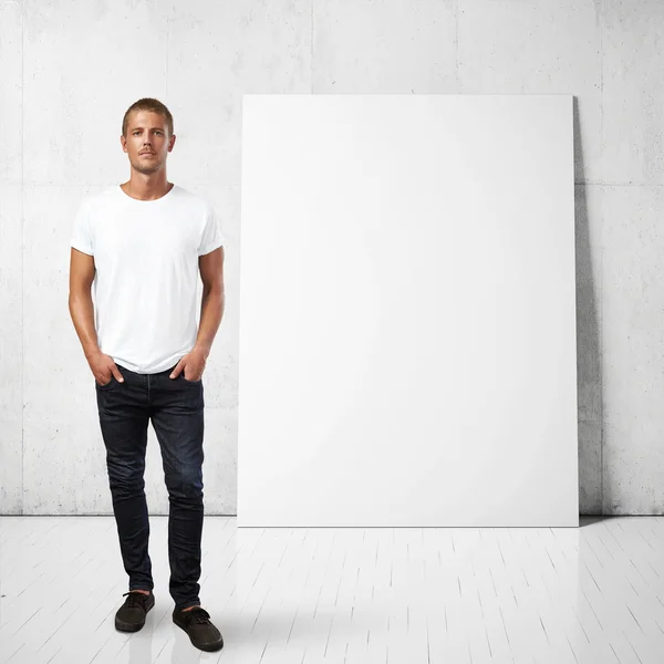 Homem e cartaz em branco em uma parede — Fotografia de Stock