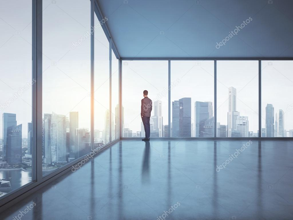 Businessman  in office and looking at city