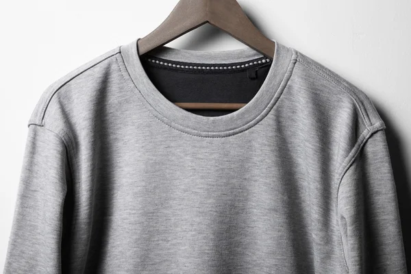 Grey jumper hanging on white wall — Stock Photo, Image