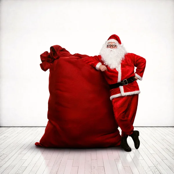 Санта Клаус опирается на огромный красный мешок — стоковое фото