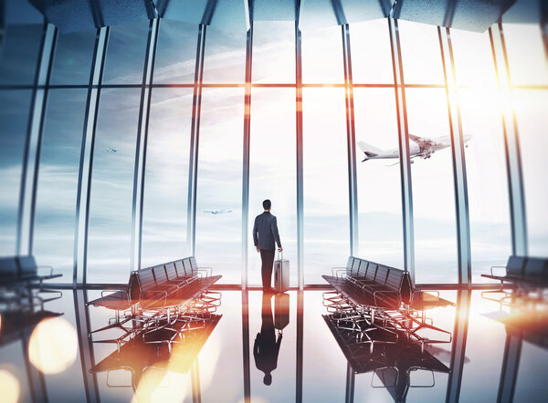Businessman at airport looking out the window to the plan