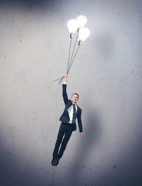 Businessman flying with light bulbs — Stock Photo, Image