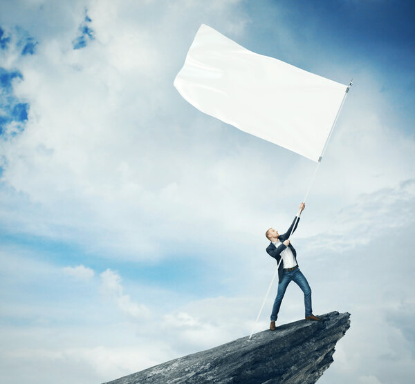 Man with white flag standing on a rock