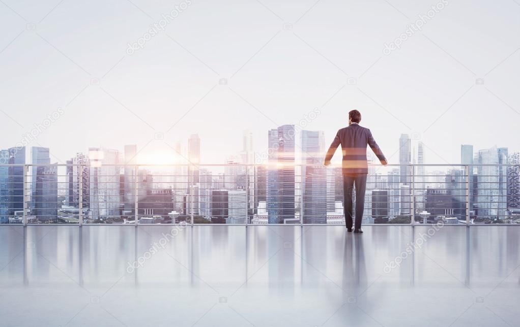 Businessman standing on a roof and looking at sunset