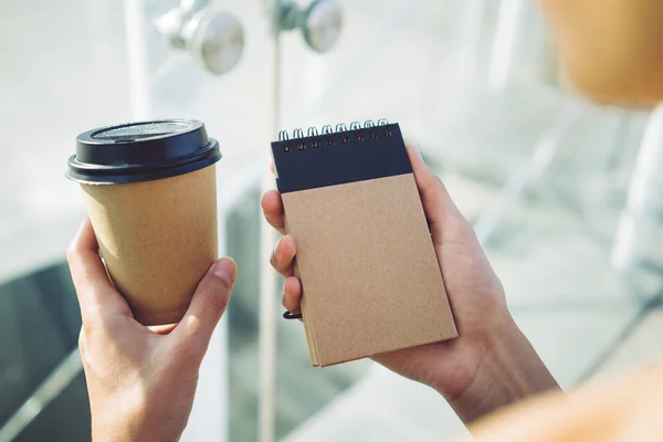 Cup of coffee and note book in hands — Stock Photo, Image