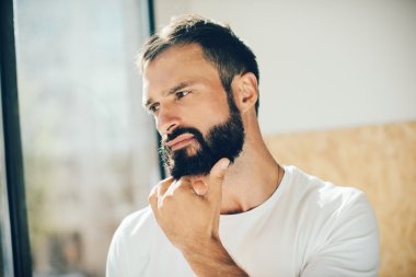 Beyaz tişörtü giyen ve seyir sakallı bir adam portresi