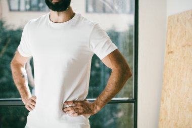 Pencere ile beyaz tshirt giyen sakallı bir adam portresi