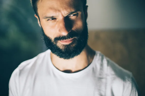 Retrato de un hombre barbudo con camiseta blanca sobre el fondo borroso —  Fotos de Stock