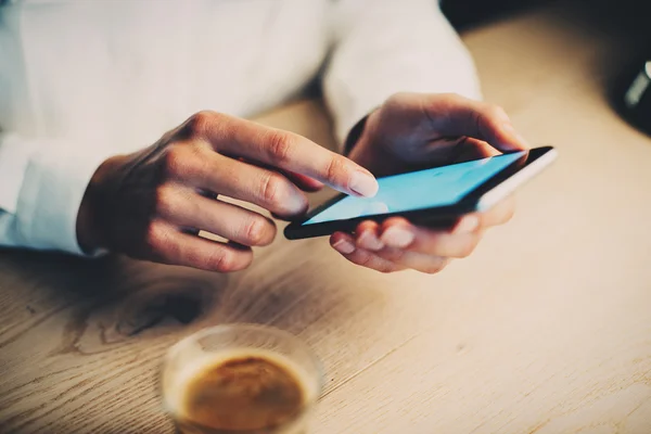 Närbild av flickan med sin smartphone och ta en kaffe — Stockfoto