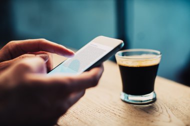 Akıllı telefon ve Kupası bir kahve kavramı fikrine masada