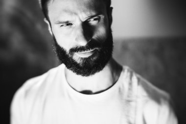 Blure arka plan üzerinde beyaz tshirt giyen sakallı bir adam portresi BW