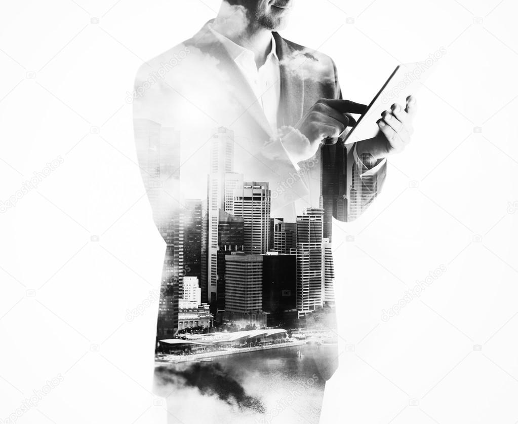 Double exposure of city and businessman using digital tablet