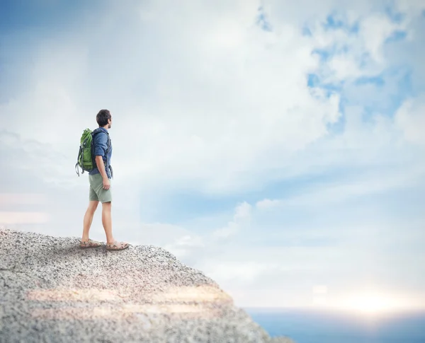 Young man with backpack on the rock — Stock Photo, Image