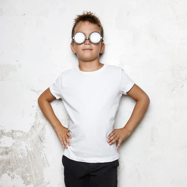 Niño en gafas se levanta sobre un fondo de pared — Foto de Stock