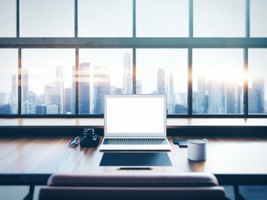 Photo of laptop on the worksplace with panoramic windows.  City at sunrise in a background. 3D rendering