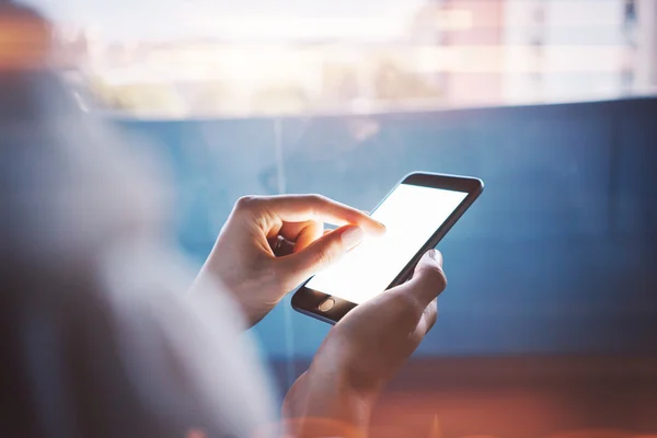 Mädchen berührt einen Bildschirm ihres Smartphones auf dem verschwommenen Hintergrund. horizontal — Stockfoto