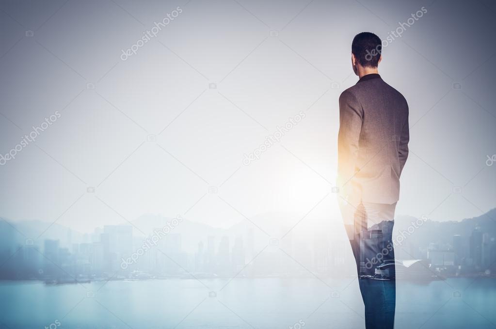 Multi exposure of young business man looking at the city