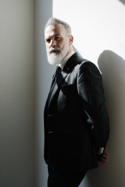 Stylish bearded man wearing trendy suit against a wall.