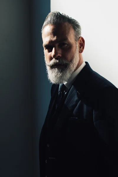 Portrait of bearded man wearing trendy suit and stands against the wall — Stock Photo, Image