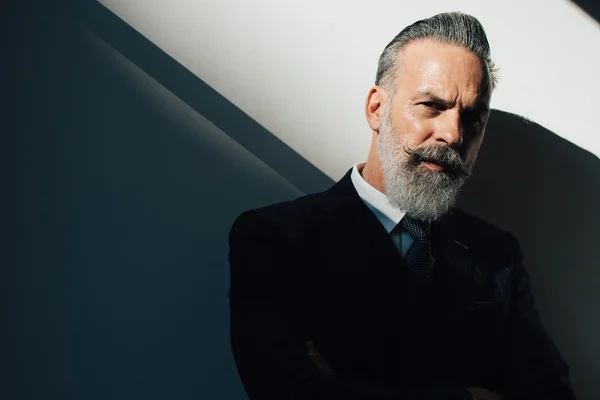 Portrait of bearded man wearing trendy suit and stands against the wall. Horizontal — Stock Photo, Image