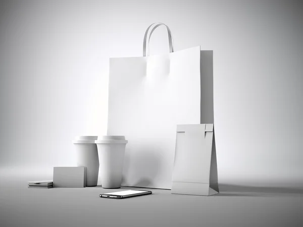 Set of white blank shopping bag, two coffee cups, business cards and generic design smartphone. Light background. 3d render — 图库照片