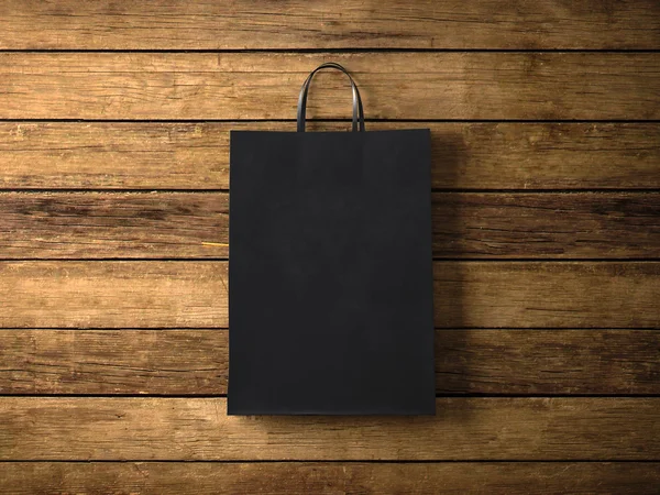 Black paper shopping bag on the wooden background. In focus. Horizontal. 3d render — Stock Fotó