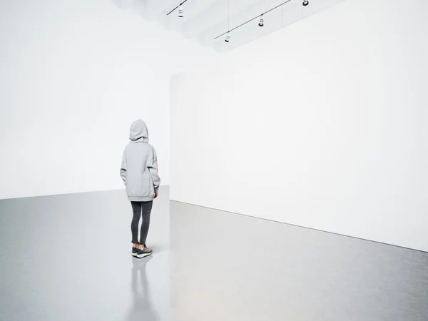 Photo of girl in modern gallery looking at the blank canvas. — Stock Photo, Image