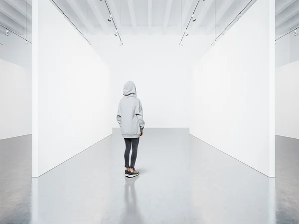 Foto da menina na galeria moderna vazia olhando para a tela em branco . — Fotografia de Stock