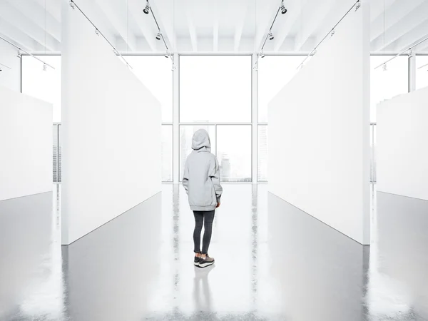 Foto da menina na galeria contemporânea vazia olhando para a tela em branco . — Fotografia de Stock