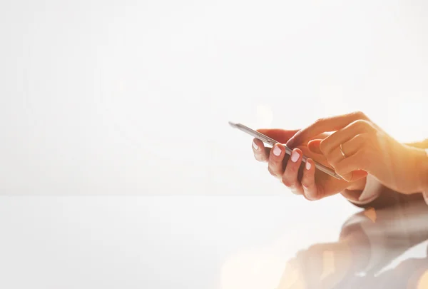 Photo rapprochée de mains féminines tapant du texte sur un smartphone. Effets visuels, fond blanc. Horizontal — Photo