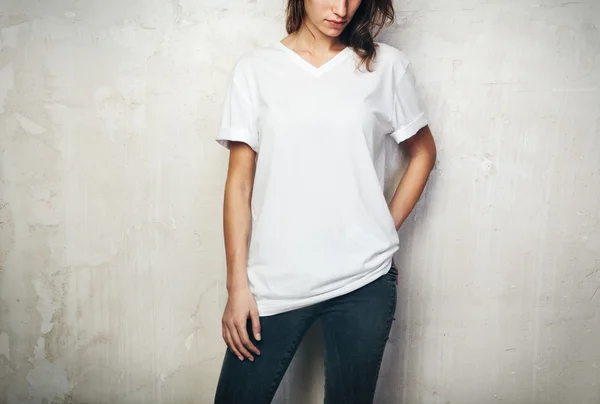 Jeune fille portant un t-shirt blanc et un jean noir. Fond de mur en béton — Photo