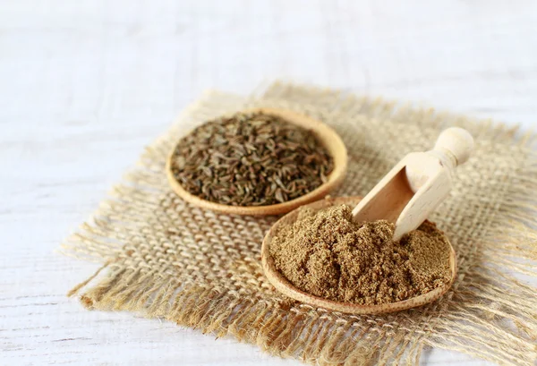 Dried cumin powder and seeds on wooden table — Stock Photo, Image