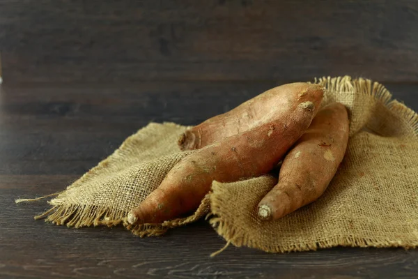 Raw sweet potatoes on wooden background — Stock Photo, Image