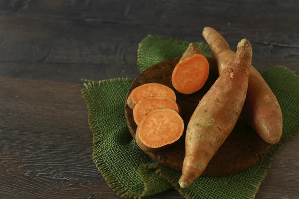 Raw sweet potatoes on wooden background — Stock Photo, Image