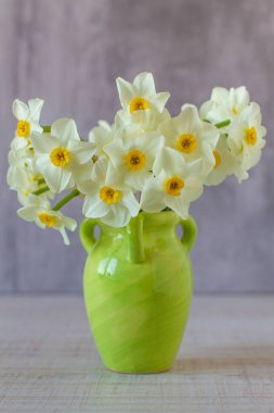 Gri arka planda vazoda küçük nergisler