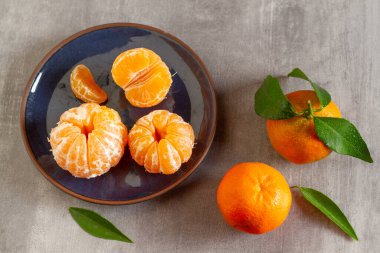 Taze mandalinalar ve yeşil yapraklı soyulmamış meyveler.