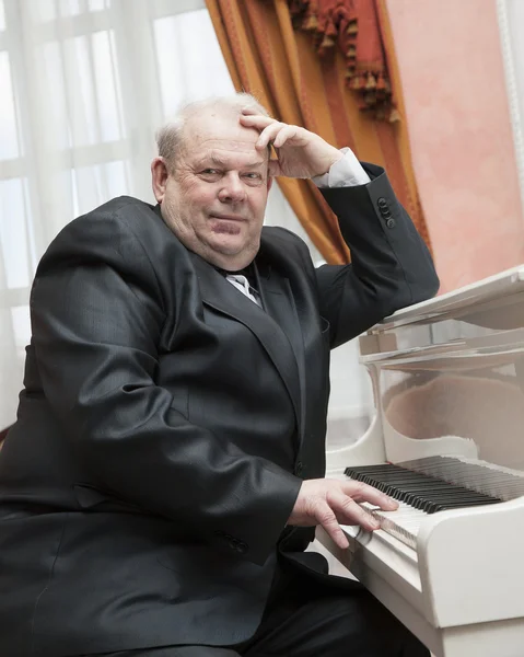 Зрелый музыкант, играющий на белом пианино — стоковое фото
