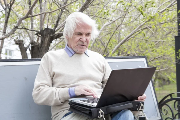 Homem sênior usando computador portátil ao ar livre — Fotografia de Stock