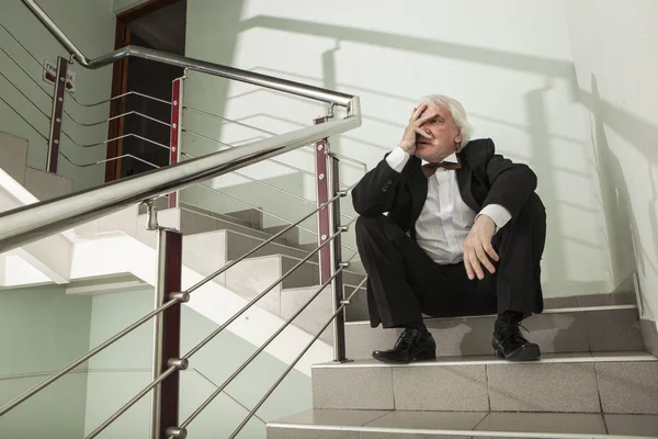 A man in a tuxedo on a metal ladder — Stock Photo, Image