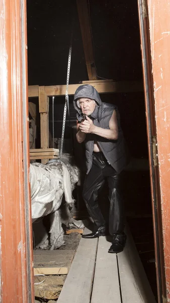 Armed robber with a gun in the attic — Stock Photo, Image